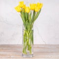 Yellow flowers, tulips in a vase. On a light background. Congratulations on Easter