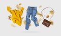 Yellow flying women`s knitted sweater blue jeans brown leather bag golden autumn leaves on gray background. Creative clothing Royalty Free Stock Photo