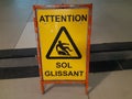 A yellow folding floor sign in french that draws attention to a freshly washed slippery floor traduction: wet floor. Royalty Free Stock Photo