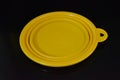 Yellow folding and multifunctional rubber plate, a bowl with a plastic edging on a black glossy surface.