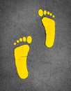 Yellow footprint painted on asphalt road. Walkway lane traffic sign. Foot mark on street texture background. Direction sign. Royalty Free Stock Photo