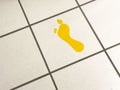 Yellow footprint on white tiled floor with grid pattern Royalty Free Stock Photo