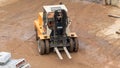 A yellow forklift operates on a construction site, where the ground is sandy and the Royalty Free Stock Photo