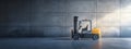 A yellow forklift is parked by a concrete wall in a warehouse Royalty Free Stock Photo