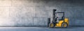 A yellow forklift is parked by a concrete wall in a warehouse Royalty Free Stock Photo