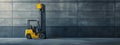 A yellow forklift is parked by a concrete wall in a warehouse Royalty Free Stock Photo