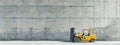 A yellow forklift is parked by a concrete wall in a warehouse Royalty Free Stock Photo