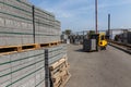 A yellow forklift rides through a warehouse past pyramid-packed packages of natural stone