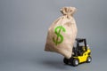 Yellow forklift truck carries a big bag of money. Attracting investment in the development and modernization of production Royalty Free Stock Photo