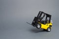 Yellow forklift truck rides on the rear wheels on gray background. Warehouse equipment, vehicle. Logistics and transport