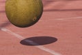 Yellow four square playground ball bouncing on red court with shadow. Exercise, fitness and fun concept