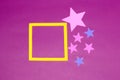 yellow frame as copy space on a purple background, around the frame stars of different sizes and colors Royalty Free Stock Photo