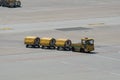 Yellow Freight trolleys with loaded baggage on the runway tarmac