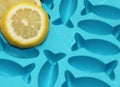 Lemon slices on turquoise wet shiny ice cube container with fish shapes for fish shaped ice cubes