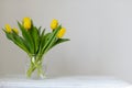 Yellow, fresh tulips in a vase on a wooden table.