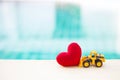 Yellow front loader truck with red heart over blurred blue water background Royalty Free Stock Photo