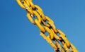 Yellow frozen old chain against a blue sky.