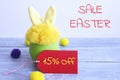 Yellow fur toy bunny in a green plastic pot on gray wooden boards, and on a gray background with the words Easter sale Royalty Free Stock Photo