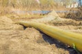 The yellow gas pipe is lying on the ground. On the background of the river and the forest Royalty Free Stock Photo