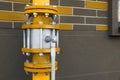 Yellow gas pipe with valve near brick wall outdoors, space for text Royalty Free Stock Photo