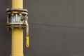 Yellow gas pipe with valve near brown wall outdoors, space for text Royalty Free Stock Photo