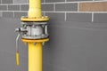 Yellow gas pipe with valve near brown wall outdoors, space for text Royalty Free Stock Photo