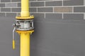 Yellow gas pipe with valve near brown wall outdoors, space for text Royalty Free Stock Photo