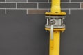 Yellow gas pipe with valve near brown wall outdoors, space for text Royalty Free Stock Photo