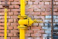 Yellow gas pipe and valve on red brick wall, copyspace Royalty Free Stock Photo