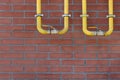 Yellow gas pipes on red brick wall outdoors, space for text Royalty Free Stock Photo