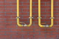 Yellow gas pipes on red brick wall outdoors Royalty Free Stock Photo