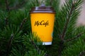 A yellow glass of McDonald's coffee on spruce paws.