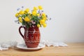 Yellow globeflowers and Forget-me-nots in a clay jug.