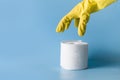 Yellow gloved hand reaches for roll of toilet paper. Close up Royalty Free Stock Photo