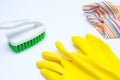 Yellow gloves with a green brush and microfiber wipe on white background, cleaning home and routine work concept Royalty Free Stock Photo