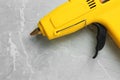 Yellow glue gun on light grey marble table, above view