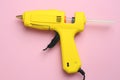 Yellow glue gun with stick on pink background, top view Royalty Free Stock Photo