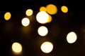 Yellow and gold lights garland in a blur on a black background. Bokeh of flying circles in the defocus. Festive atmosphere of Chri