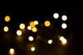 Yellow and gold lights garland in a blur on a black background. Bokeh of flying circles in the defocus. Festive atmosphere of Chri Royalty Free Stock Photo