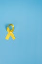 Yellow gold ribbon on a yellow background. Children cancer concept. Awareness month. Childhood Cancer Day February, 15. Vertical,