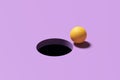 Yellow golf ball standing at the edge of the black hole on purple background. 3d rendering
