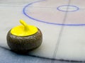 Yellow granite stone for curling game on the ice