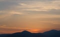 Yellow-gray sunset sky with light clouds over the mountains and the sea