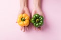 Yellow and green bell pepper holding by hand on pink background Royalty Free Stock Photo