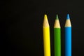 yellow, green and blue coloured pencil crayons on a black background Royalty Free Stock Photo