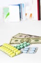 Yellow green blue medical pills and american dollars on white background Royalty Free Stock Photo