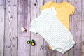 Yellow and green bodysuit made of cotton with a children`s toy. Clothes for newborns on a gray background. copy space Royalty Free Stock Photo