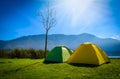 Yellow and green camping tent on grass near mountain river in mo