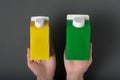 Yellow and green carton box or packaging of tetra pack in a female hands. Black background