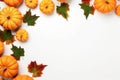 Yellow and green dried leaves and small orange pumpkins on white background, top view, copy space. Halloween, Thanksgiving holiday